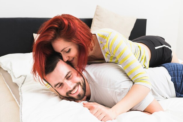 Femme embrassant son mari sur le lit