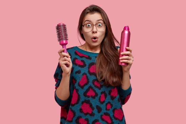 Photo gratuite femme émotive stupéfaite émotionnelle dans un salon de beauté, surprise par une nouvelle coiffure, regarde avec des yeux écarquillés, vêtue d'un pull avec des taches roses