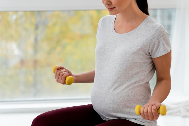 Femme enceinte à l'aide de poids jaunes