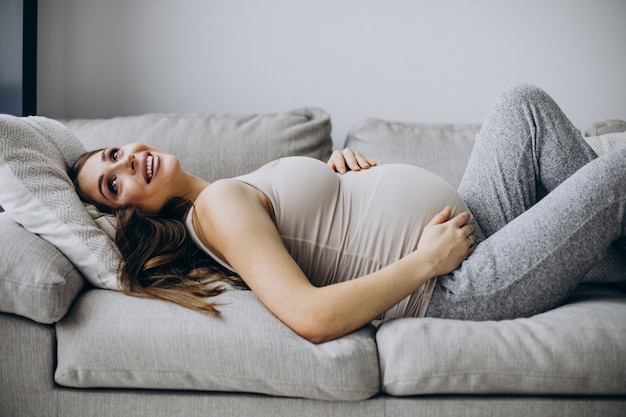 Femme enceinte allongée sur l'entraîneur à la maison