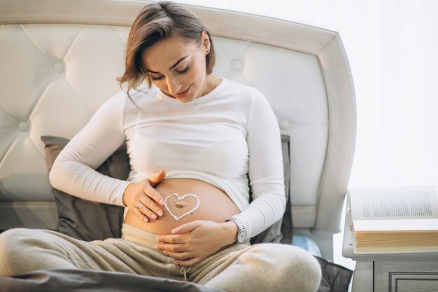 Femme enceinte appliquant de la crème sur le ventre pour éviter les étirements