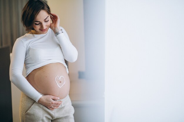 Femme enceinte appliquant de la crème sur le ventre pour éviter les étirements