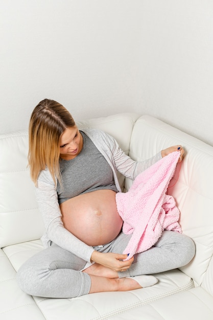 Femme enceinte assise sur un canapé et regardant une couverture