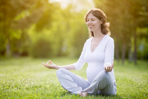 Femme enceinte en bonne santé se détendant sur l&#39;herbe dans le parc