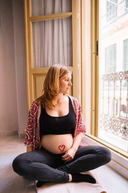 Femme enceinte à côté de la fenêtre ouverte