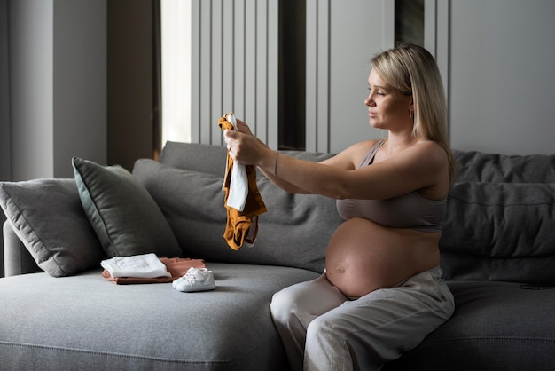 Femme enceinte de coup moyen regardant des vêtements