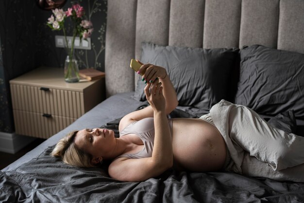 Femme enceinte de coup moyen avec téléphone