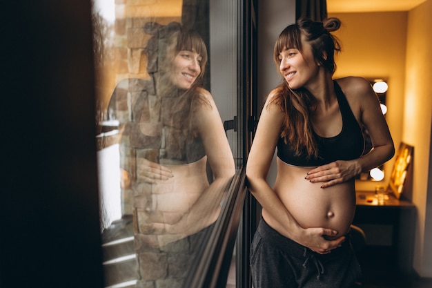 Photo gratuite femme enceinte debout près de la fenêtre