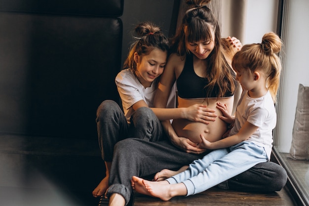 Femme enceinte avec des enfants assis près de la fenêtre