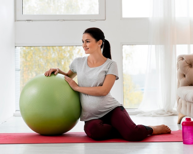 Femme enceinte exerçant avec ballon de fitness vert