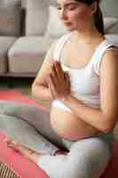 Photo gratuite femme enceinte faisant du yoga à la maison