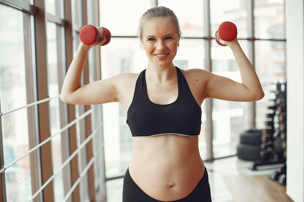 Une femme enceinte fait du sport avec des dambbels