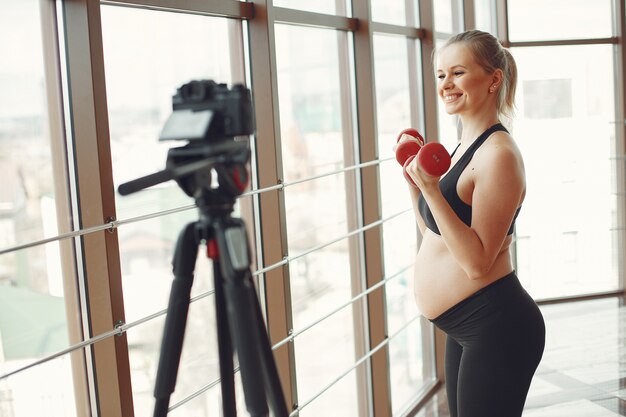 Une femme enceinte fait du sport avec des dambbels