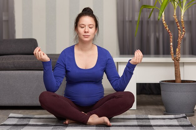 Femme enceinte insouciante détendue assis en posture de lotus