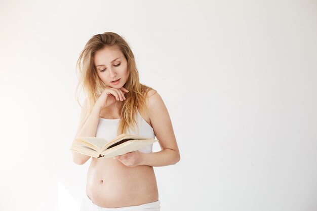 Femme enceinte lisant un livre en faisant semblant d'être un mannequin ou une blogueuse beauté