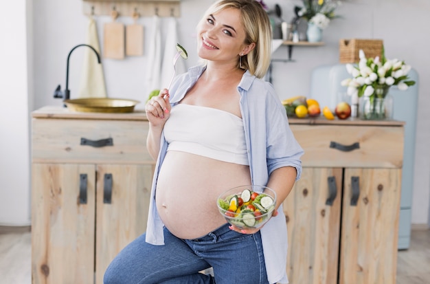 Femme enceinte manger de la salade en regardant la caméra