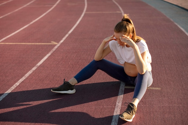 Photo gratuite femme enceinte prenant une pause de l'exercice à l'extérieur