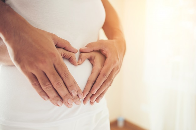 Femme enceinte et son mari main montrant la forme de cœur.