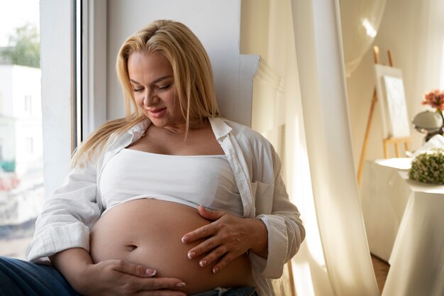 Une femme enceinte de taille moyenne passe du temps à l'intérieur.