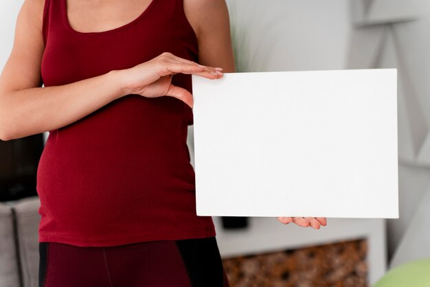 Photo gratuite femme enceinte tenant une carte blanche à côté d'elle