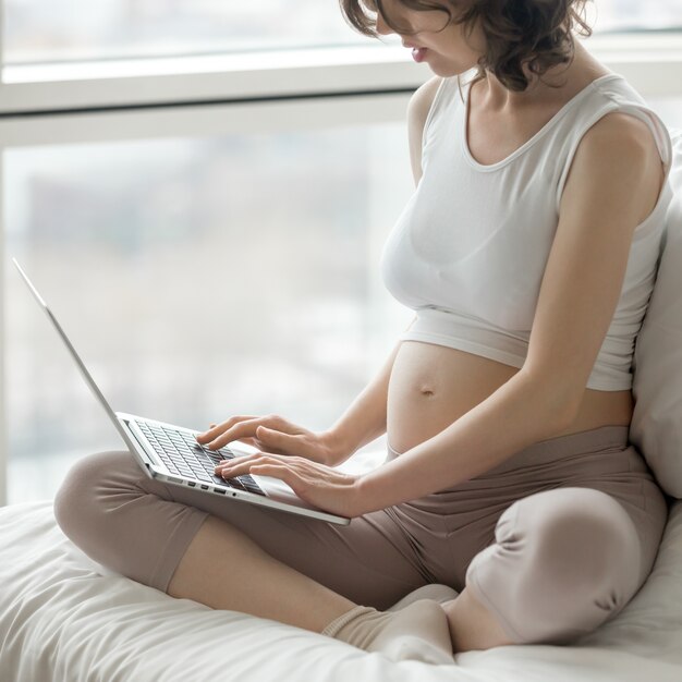 Femme enceinte travaillant sur ordinateur à la maison