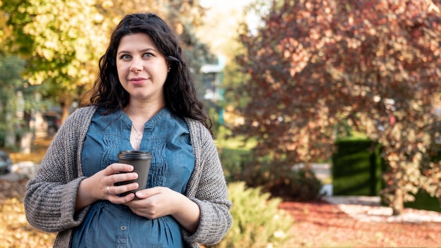 Femme enceinte vue de face avec une tasse de café posant