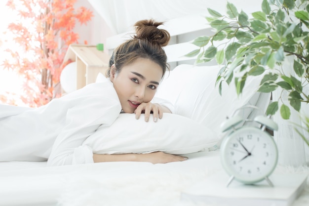 femme endormie dans son lit pendant que son réveil indique l&#39;heure à la maison dans la chambre