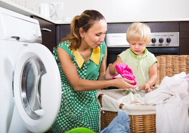 Femme avec enfant près de la machine à laver