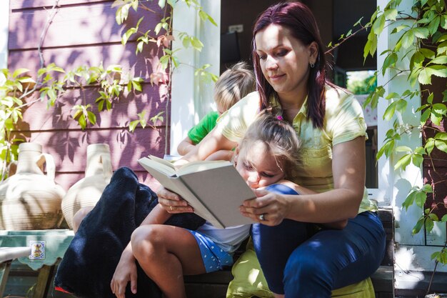 Femme avec des enfants qui lisent sur le porche