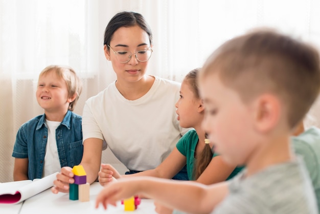 Femme enseignant aux enfants comment jouer avec un jeu coloré