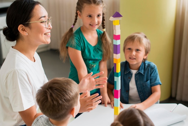 Femme enseignant aux enfants comment jouer avec la tour colorée