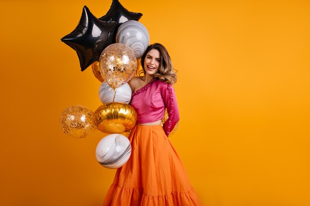 Femme enthousiaste posant avec des ballons pour son anniversaire