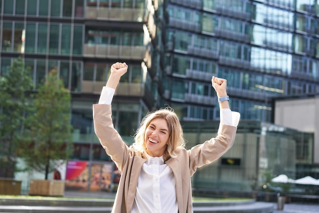 Femme d'entreprise célébrant sa victoire à l'extérieur sur la rue heureuse femme d'affaires levant les mains et t