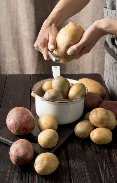 Femme éplucher des pommes de terre crues