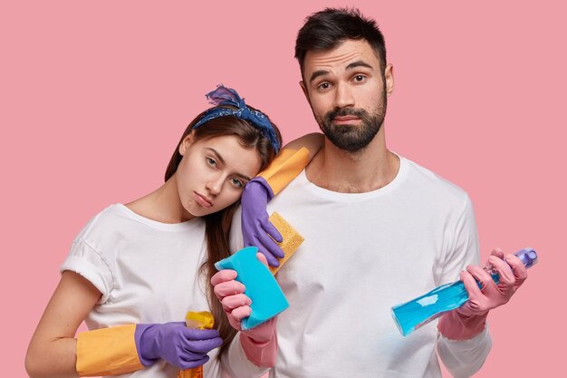 Photo gratuite une femme épuisée se penche sur l'épaule de son mari, se sent fatiguée après un grand nettoyage, se sent mécontente et contrariée, porte un t-shirt décontracté