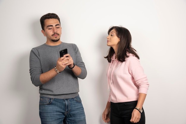 Femme essayant de regarder dans son téléphone sur blanc.