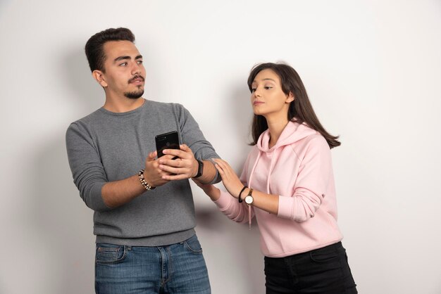 Femme essayant de regarder dans son téléphone sur blanc.