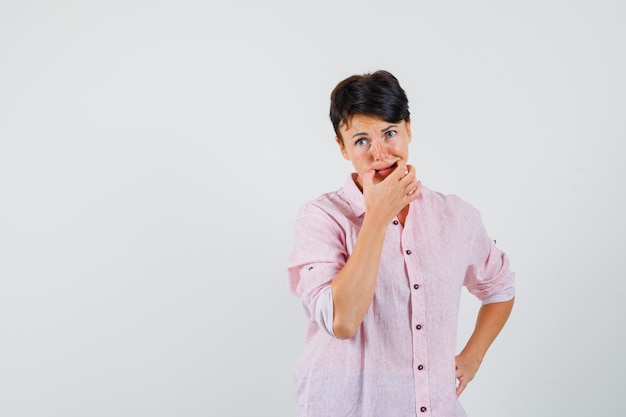 Femme essayant de siffler en chemise rose et à la pensif. vue de face.