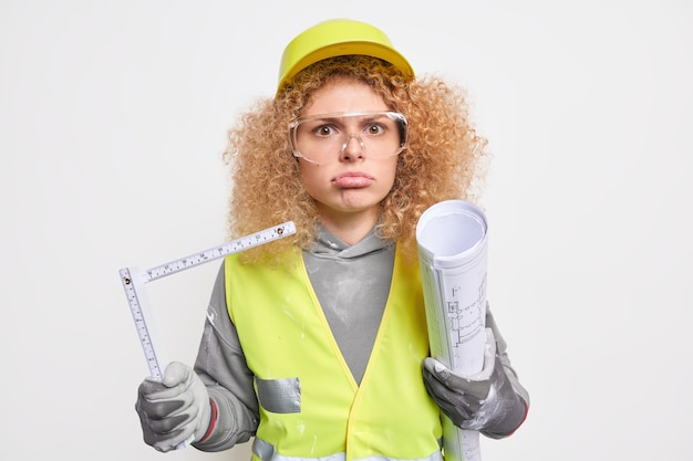 Femme Est Titulaire D'un Plan Papier Et D'un Ruban à Mesurer Occupé à Faire La Reconstruction De La Maison Prépare Le Plan Architectural Porte Un Casque Uniforme