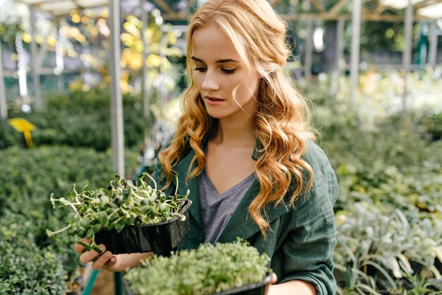 une femme est venue au magasin de plantes pour choisir la fleur pour elle-même à la maison. La fille pensive aime le choix.