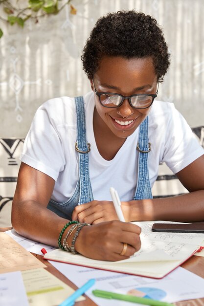 Femme ethnique joyeuse créative avec une coiffure courte et bouclée