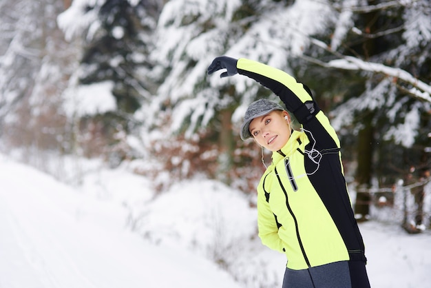 Femme étirant ses bras et ses mains dans la forêt d'hiver