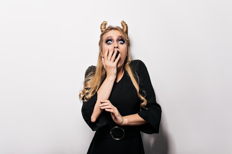 Photo gratuit femme étonnée en robe élégante posant à l'halloween. belle sorcière exprimant des émotions surprises.