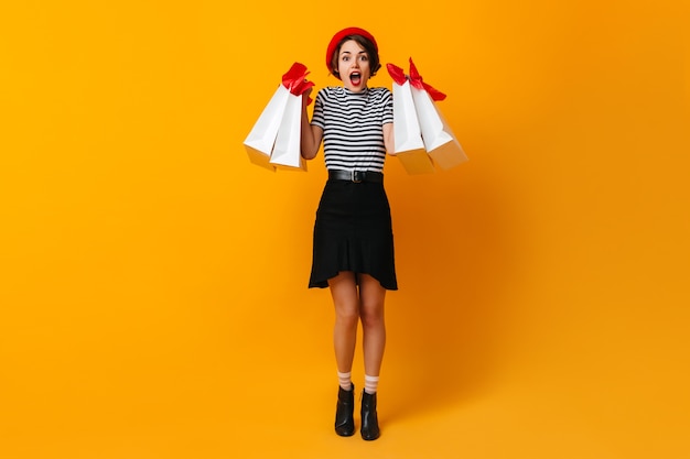 Femme étonnée en t-shirt rayé posant après le shopping