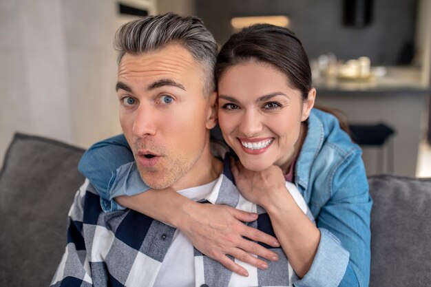 Femme étreignant un homme gai regardant la caméra