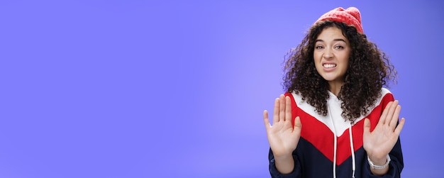 Photo gratuite femme européenne mécontente aux cheveux bouclés levant les paumes près de la poitrine et agitant en signe de refus et de rejet