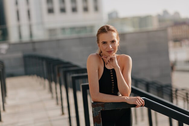 Femme européenne posant à la caméra avec le sourire tout en s'entraînant à l'extérieur en journée ensoleillée