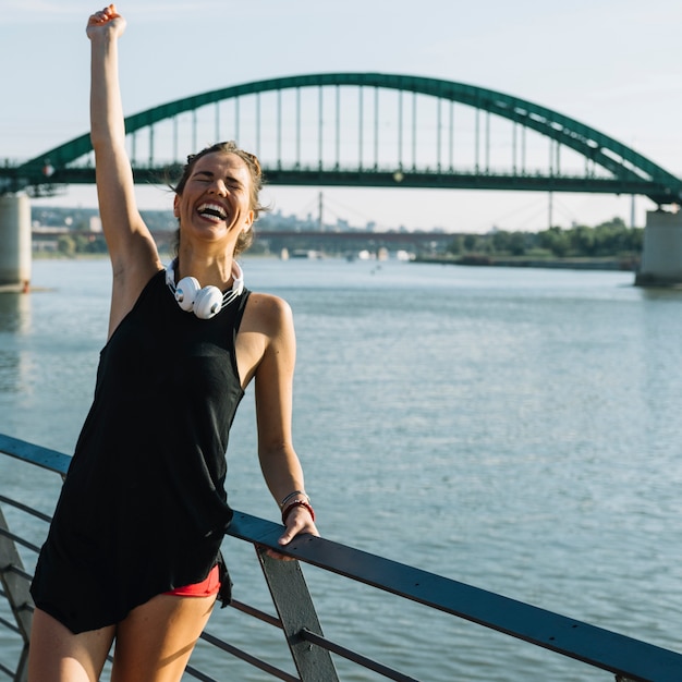 Femme excitée levant les bras devant la rivière