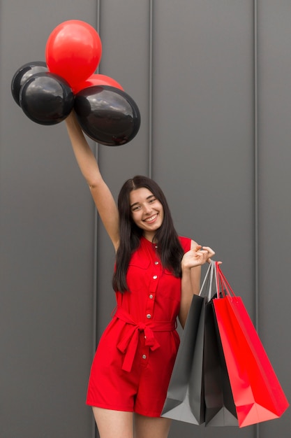 Photo gratuite femme excitée tenant des ballons et des sacs à provisions vue de face