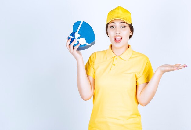 Femme excitée tenant une boîte-cadeau sur un mur blanc